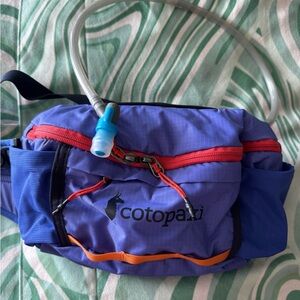 Cotopaxi 2L purple hydro hip pack with red and orange accents.